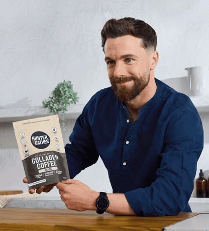 Man holding a package of 'Hunter Gather' Collagen Coffee in a kitchen setting.