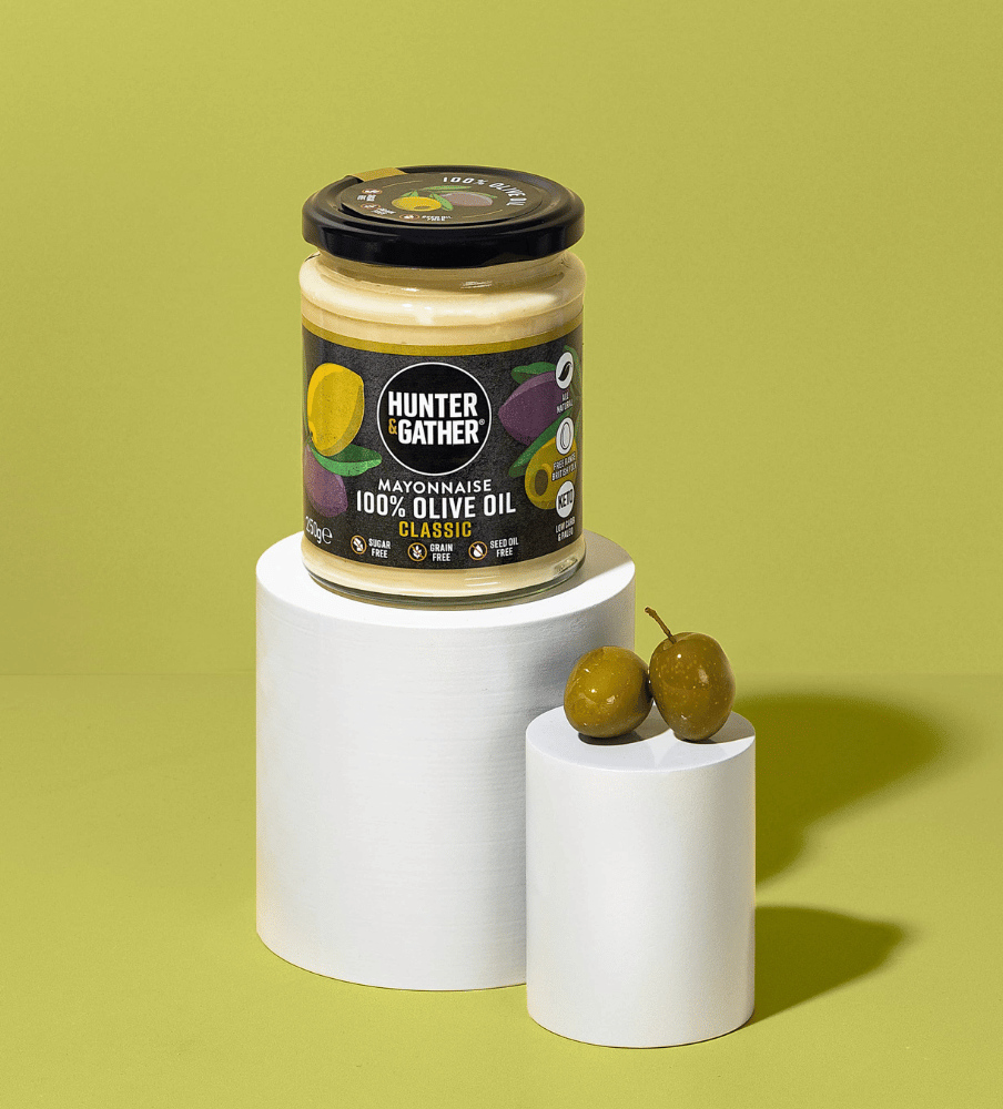 Jar of Hunter & Gather mayonnaise with olives on a green background