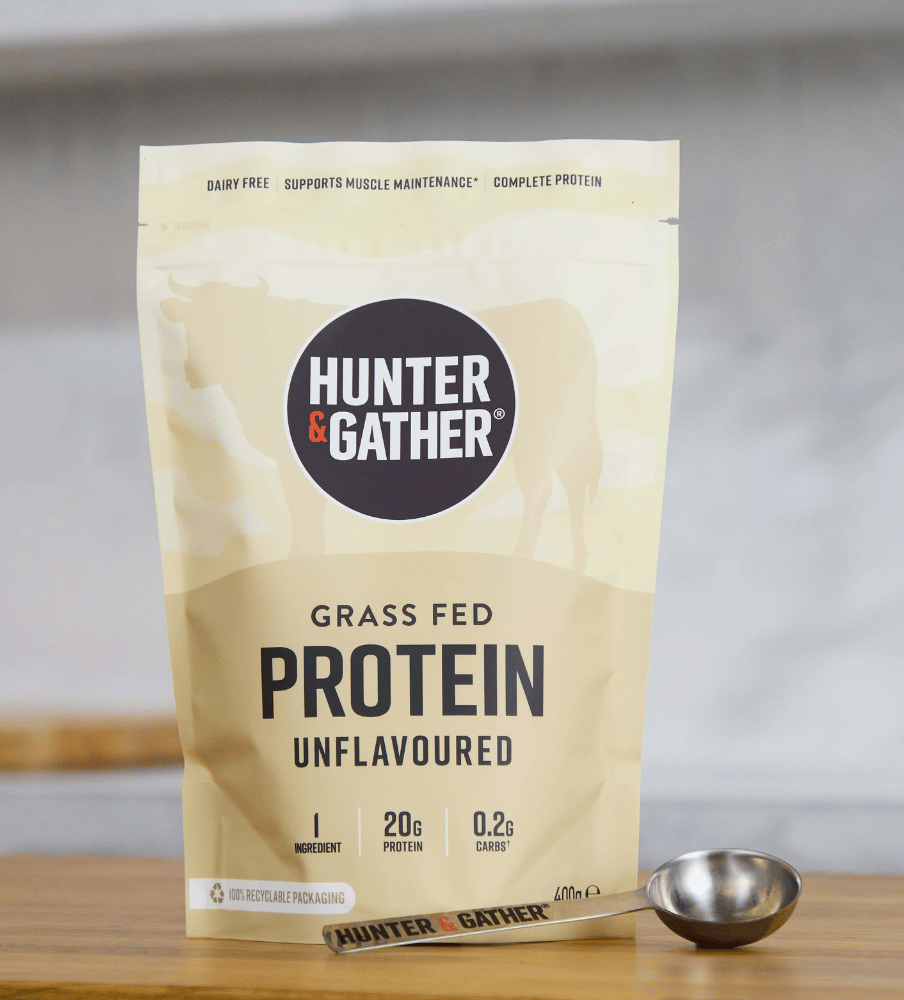 Hunter & Gather grass fed protein package on a wooden surface with a spoon.