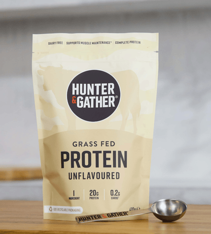 Hunter & Gather grass fed protein package on a wooden surface with a spoon.