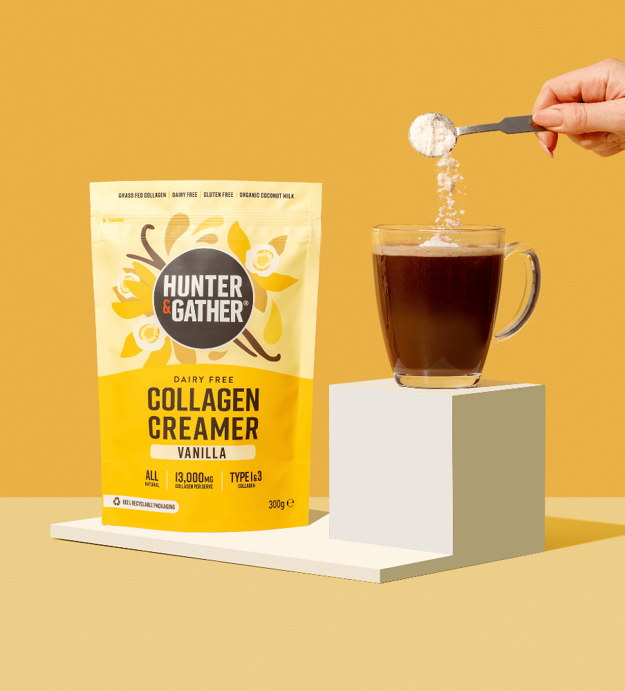 eu-en | Hunter & Gather Collagen Creamer package with a cup of coffee and a hand pouring creamer into it on a yellow background.